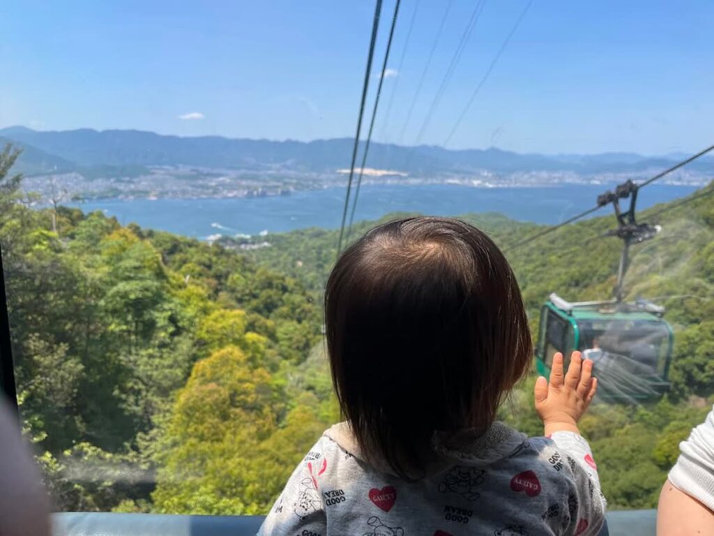 【厳島神社&錦帯橋旅log】山口と広島の名所を巡る旅|じーじとばーばとの家族旅行第4弾 2025.5.31-6.1 6 下りのロープウェーから宮島の景色を見る子供の画像