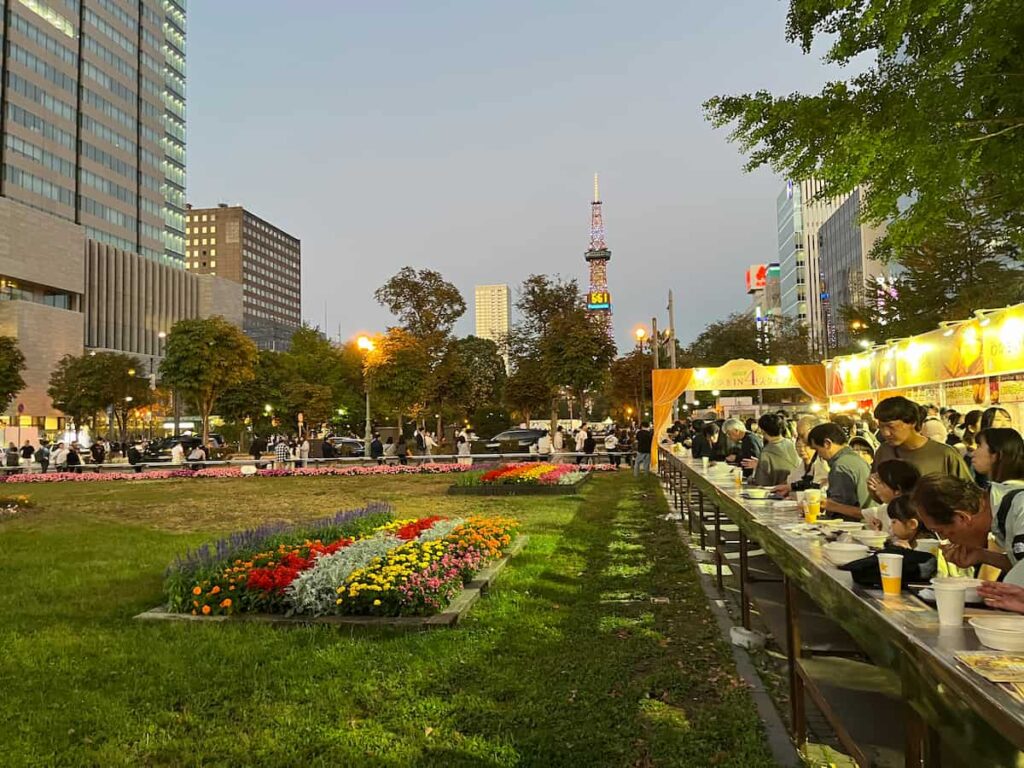 夕方の大通公園のオータムフェスト会場とテレビ塔の写真